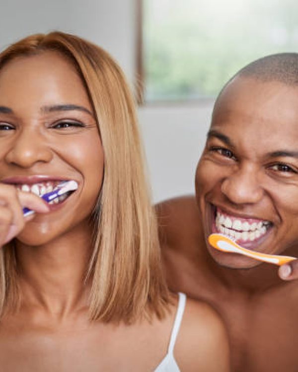 Portrait of a young couple brushing their teeth together in the bathroom at home